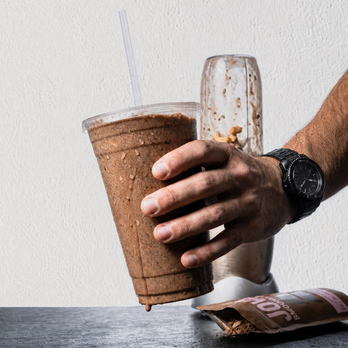A man's hand gripping a thick JOVA smoothie
